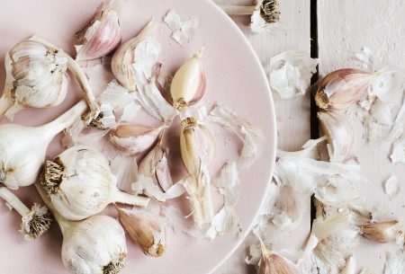 View Garlic & the low-FODMAP diet Garlic cloves and bulbs on plate and white wooden surface