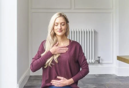 Dr Megan Rossi sitting cross-legged on the ground in a mindful yoga pose