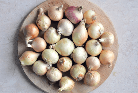 A wooden plate full of onions