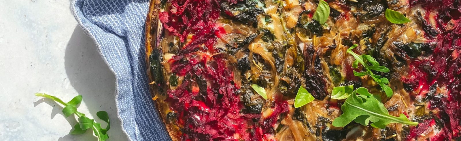 Fresh cooked full moreish spiced beetroot tart on bench with blue serving towel