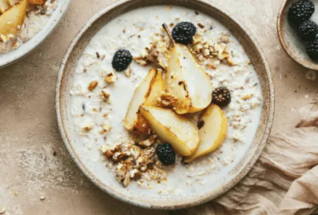 Full bowl of porridge on benchtop with fresh fruits and seeds scattered on top