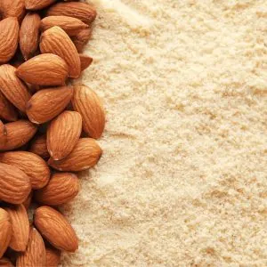 A photo of ground almonds with whole almonds next to it