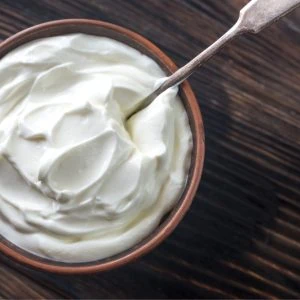 A photo of greek yoghurt in a bowl with a spoon sticking out