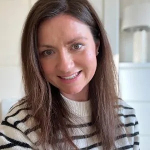 A photo of Shelley smiling. She has brunette, mid-length hair and is wearing a striped top.