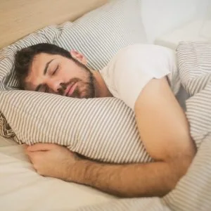 A photo of a man sleeping comfortably in bed