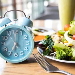 A photo of a clock next to plate full on food