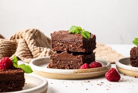 A photo of two brownies on a plate with raspberries and mint