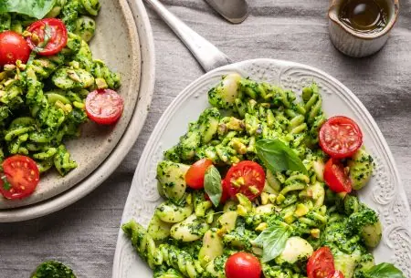 A photo of pesto pasta on two plates laid on a table