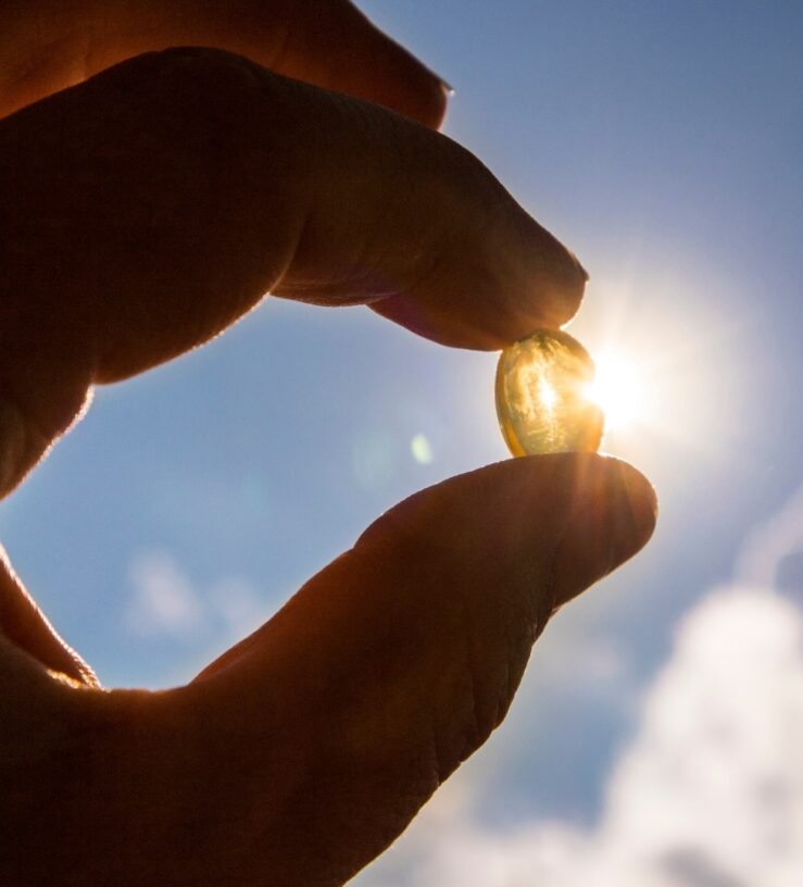 A photo of someone holding up vitamin D towards the sun