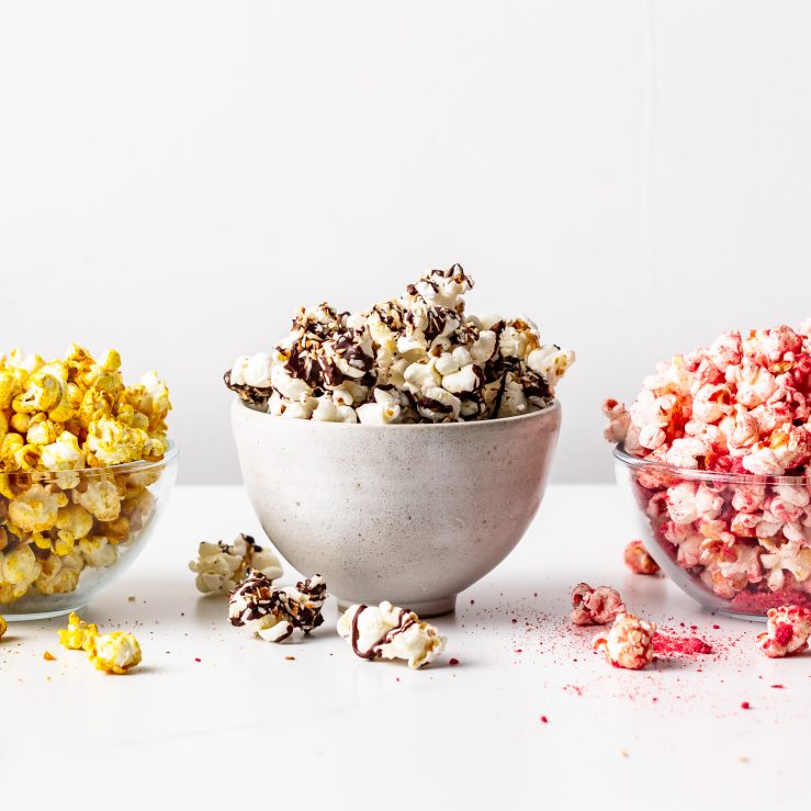 Three bowls of popcorn with the three different toppings on each