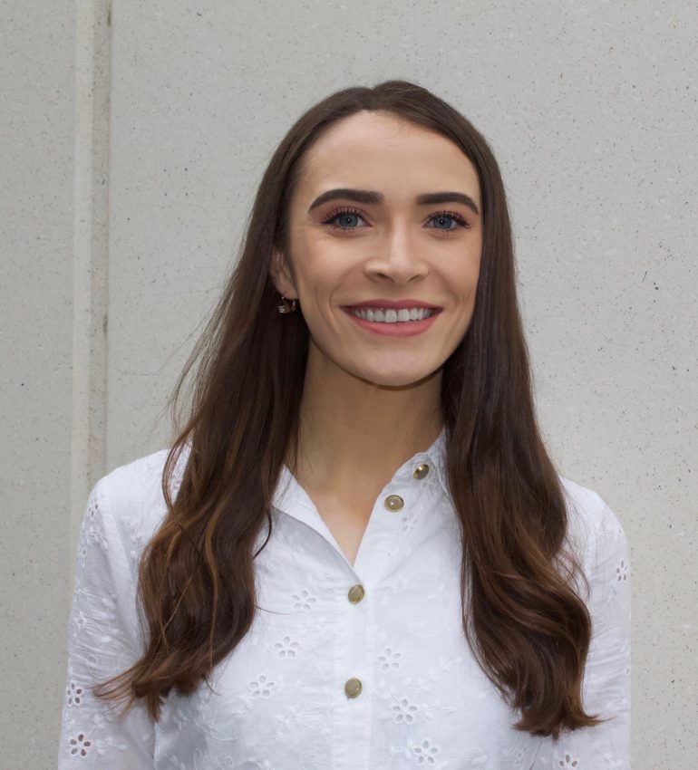 A photo of Estelle smiling, she has brunette, long hair and blue eyes