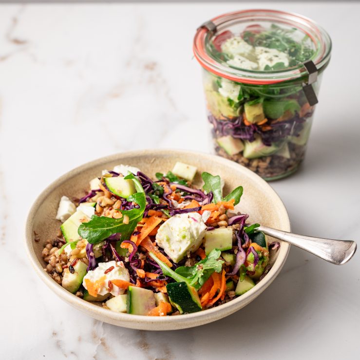 A bowl of the zingy salad with a jar in the background