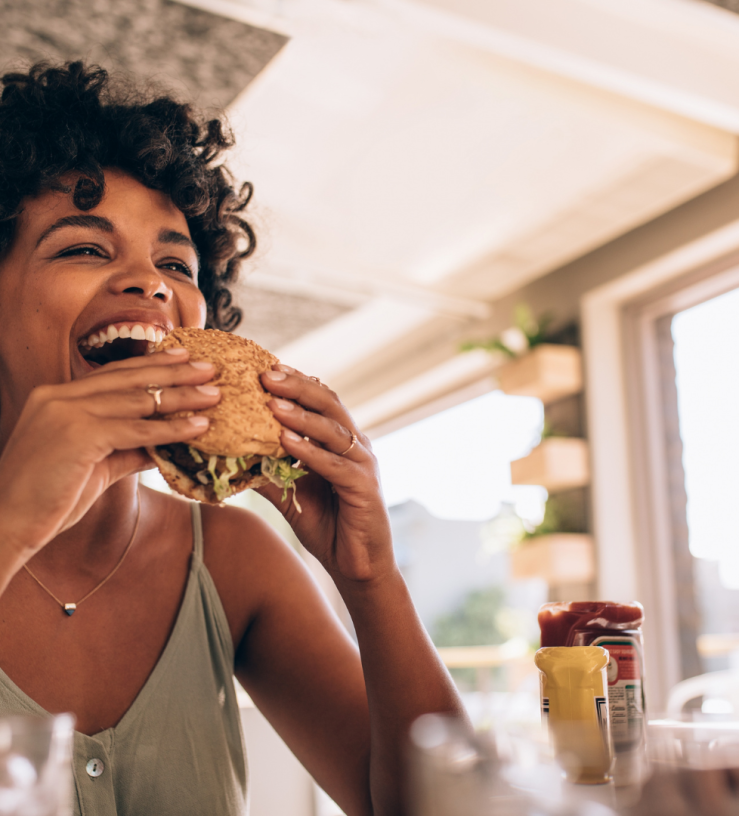 Photo of a woman enjoying eating a sandwich to show workplace wellbeing