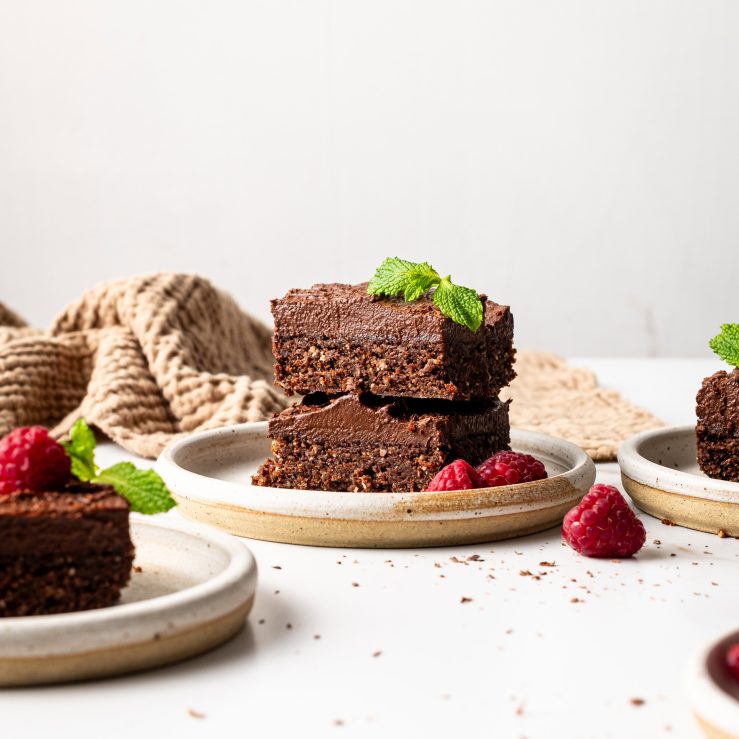 A photo of two brownies on a plate with raspberries and mint