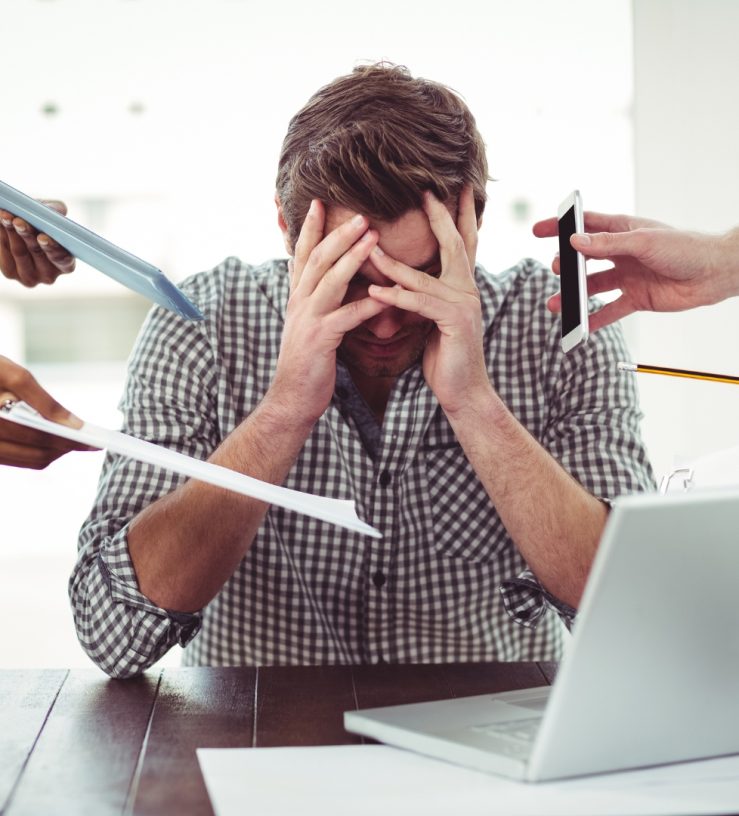 A man in front of his laptop with his head in his hands