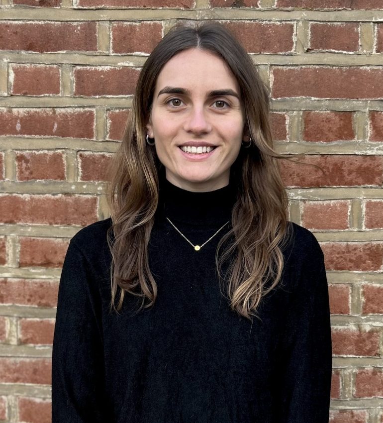 A photo of Amy Buckley smiling, she has brunette, long hair with blonde highlights and brown eyes