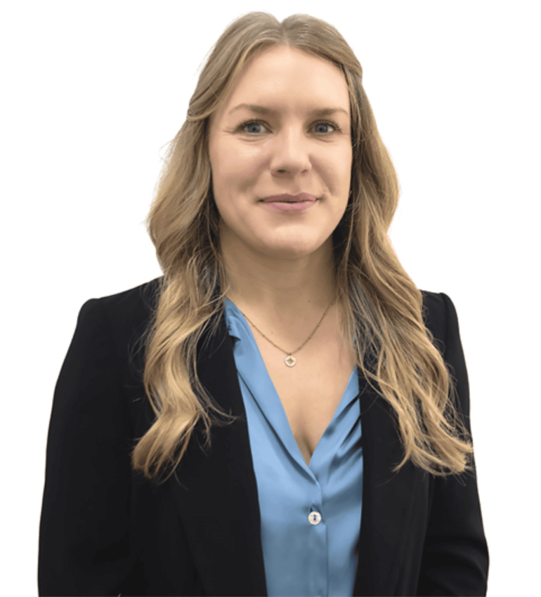 A photo of Emily, who has blonde hair and ,blue eyes, smiling. She is wearing a black blazer and a professional, light blue blouse