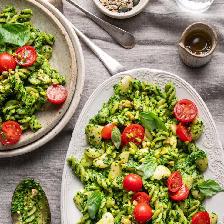 A photo of pesto pasta on two plates laid on a table