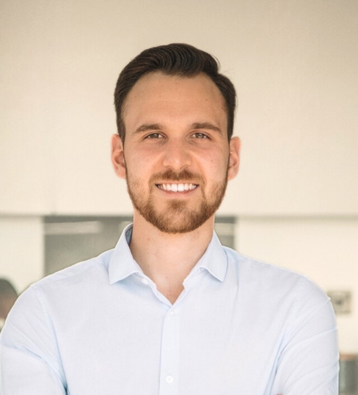 Joe Alvarez has short brown hair. He is wearing a smart white shirt and smiling at the camera